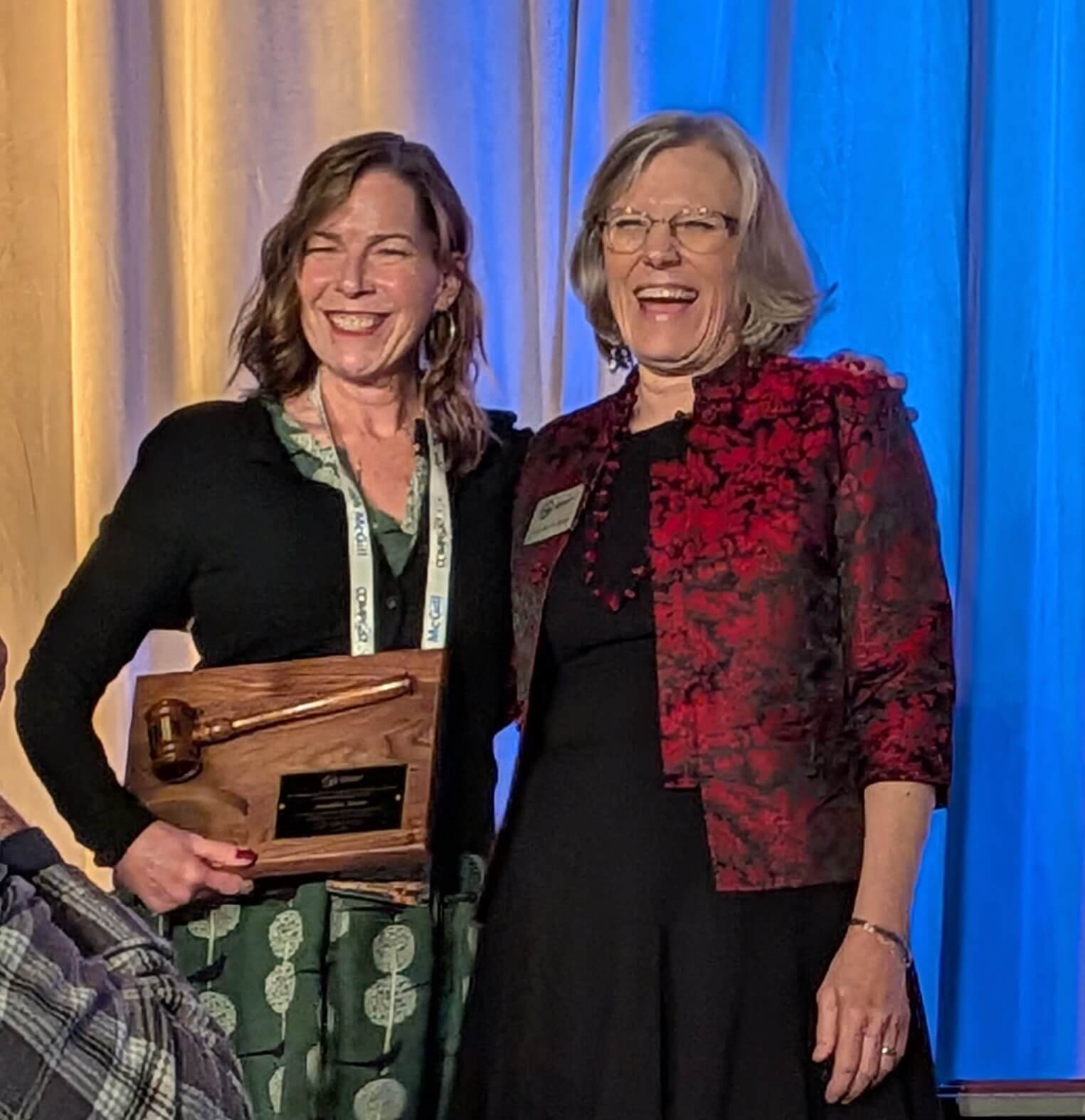 two women holding a plaque