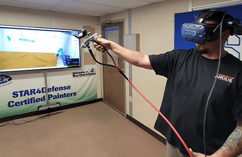 a man wearing virtual reality goggles and vr paint gun demonstrate the VirtualPaint painter training system