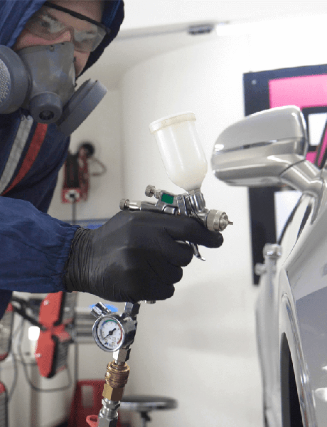 Painter wearing proper protective equipment paints automobile door