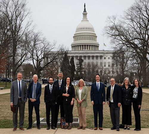 posed group of eleven women and men in professional dress with White House in the background
