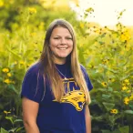 young girl in purple shirt standing in front of green and yellow prairie