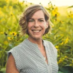 Author Jennifer Trent, IWRC Program Manager standing in front of yellow and green prairie