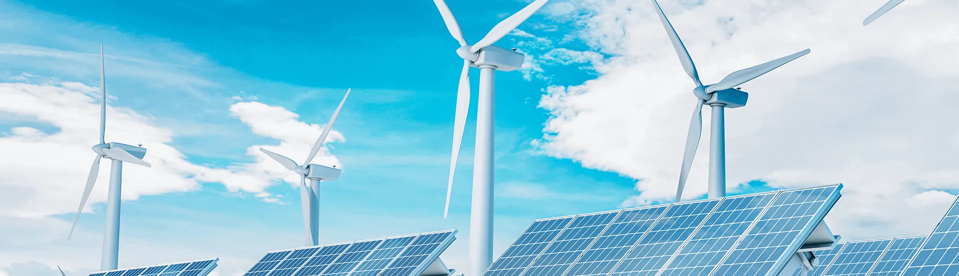 Windmills and solar panels against blue sky