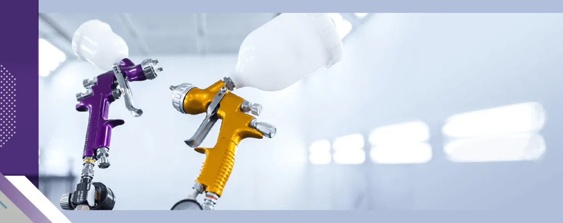 Two gravity feed paint guns used for painting vehicles shown inside spray booth